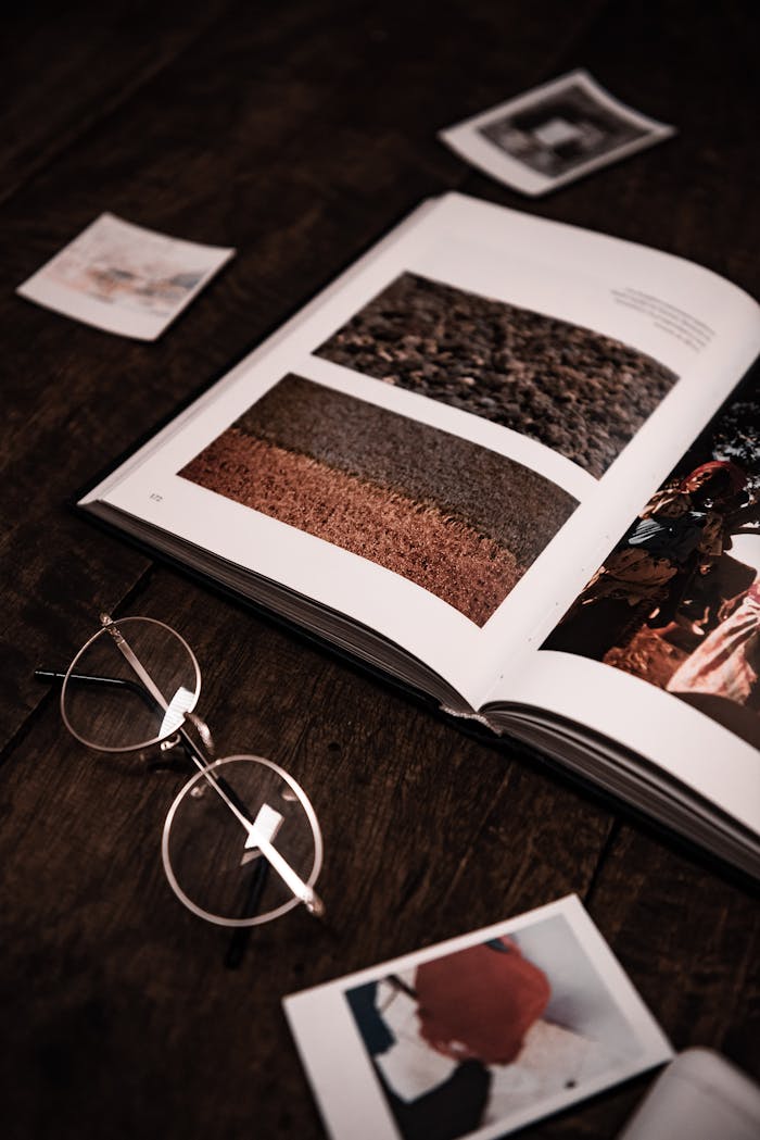 Stylish flat lay of eyeglasses and an open magazine on a wooden surface.
