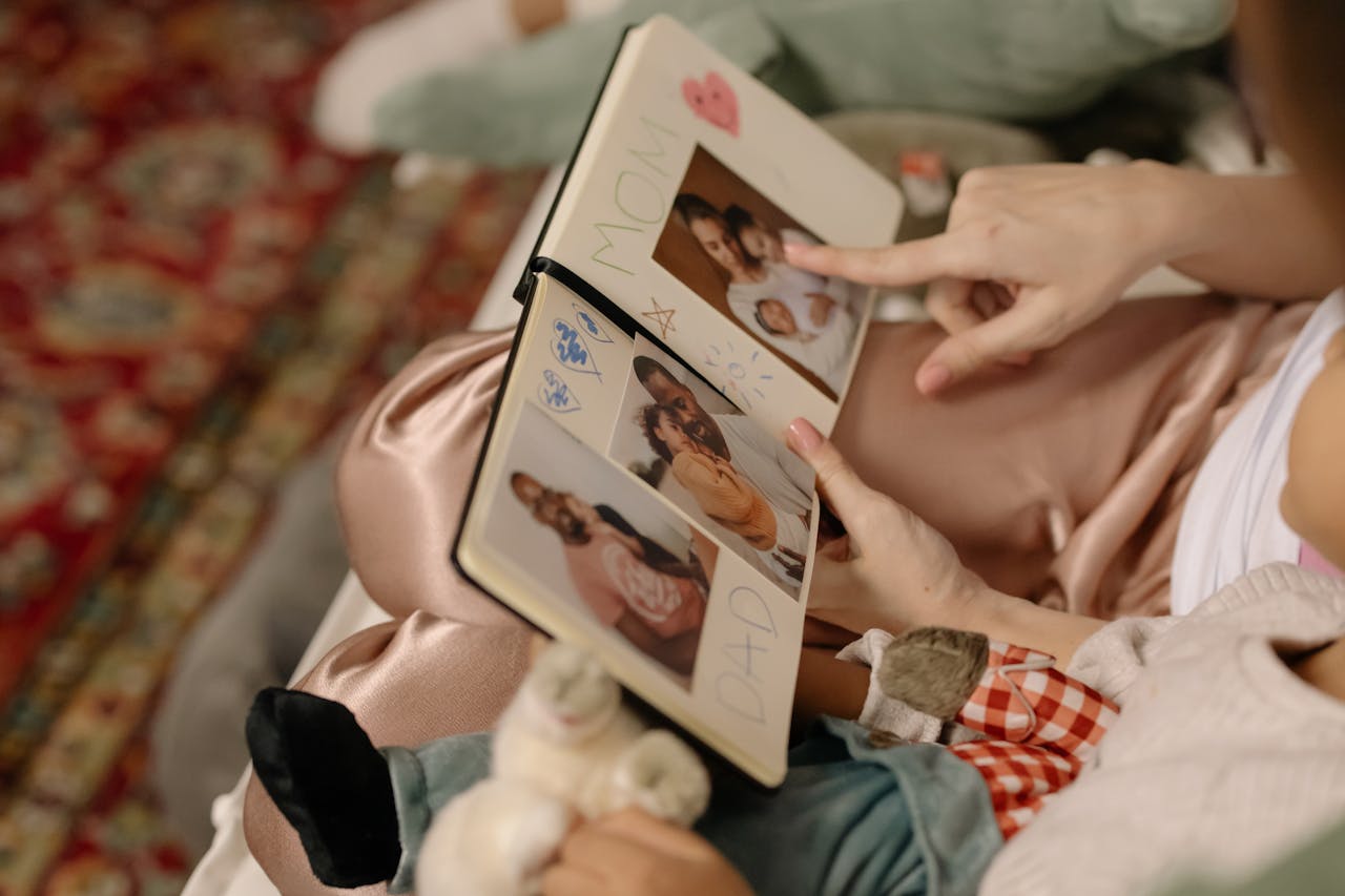 A child and parent bonding over a family photo album indoors.